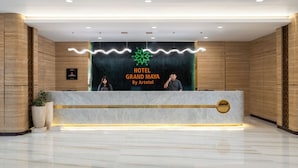 Una recepción de hotel con diseño moderno, un logo y un cartel con el nombre del hotel.