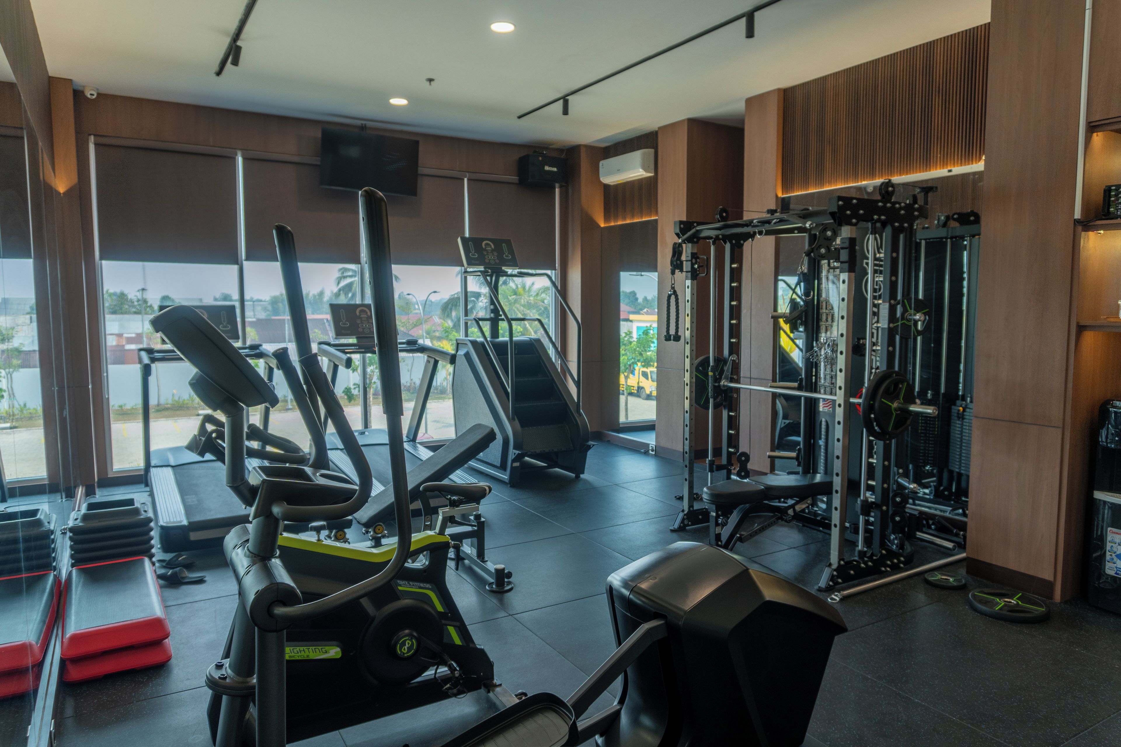 A gym with exercise equipment, large windows, and a view of the outside.