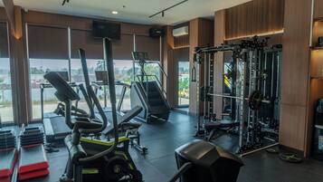 A gym with exercise equipment, large windows, and a view of the outside.