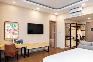 A hotel room with a bed, a desk with a chair, a television, a bench, a wardrobe, and a mirror. - Grand Maya by ARTOTEL - Banjarbaru (Banjarbaru)
