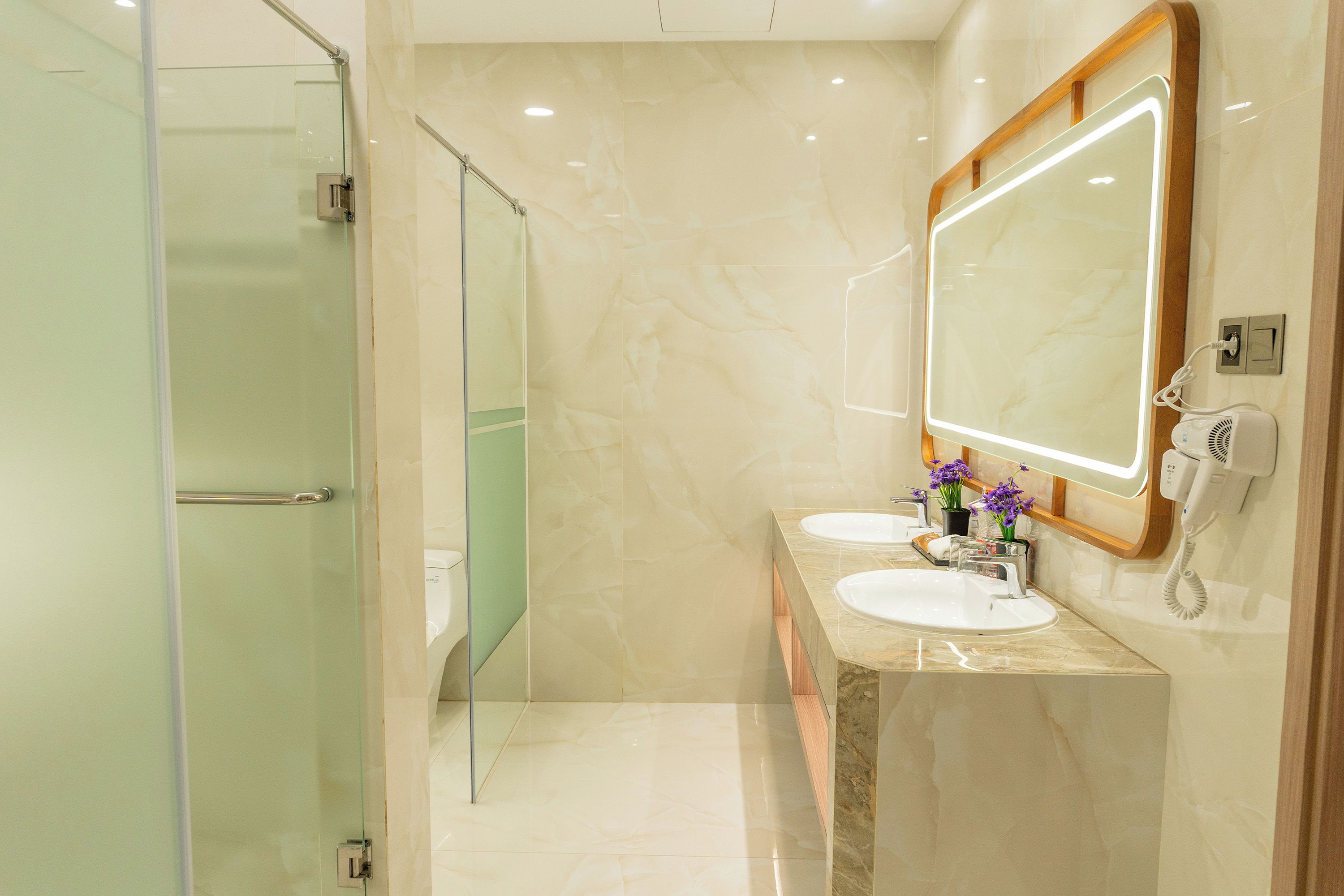 A bathroom with a glass shower enclosure, a double sink vanity, and a large mirror.