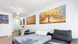 Ein Schlafzimmer mit einem Bett, einem grauen Sofa und drei Bildern an der Wand.