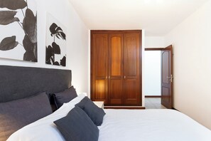 A bedroom with a large bed, dark headboard, and a wooden wardrobe. - Home2Book Villa Jazmín Real Heated pool & views (Arafo)