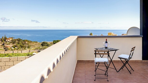 Un balcone con tavolo e sedie, vista sulla costa.
