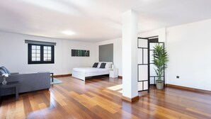 Un'ampia stanza con un letto, una poltrona e una pianta in vaso.