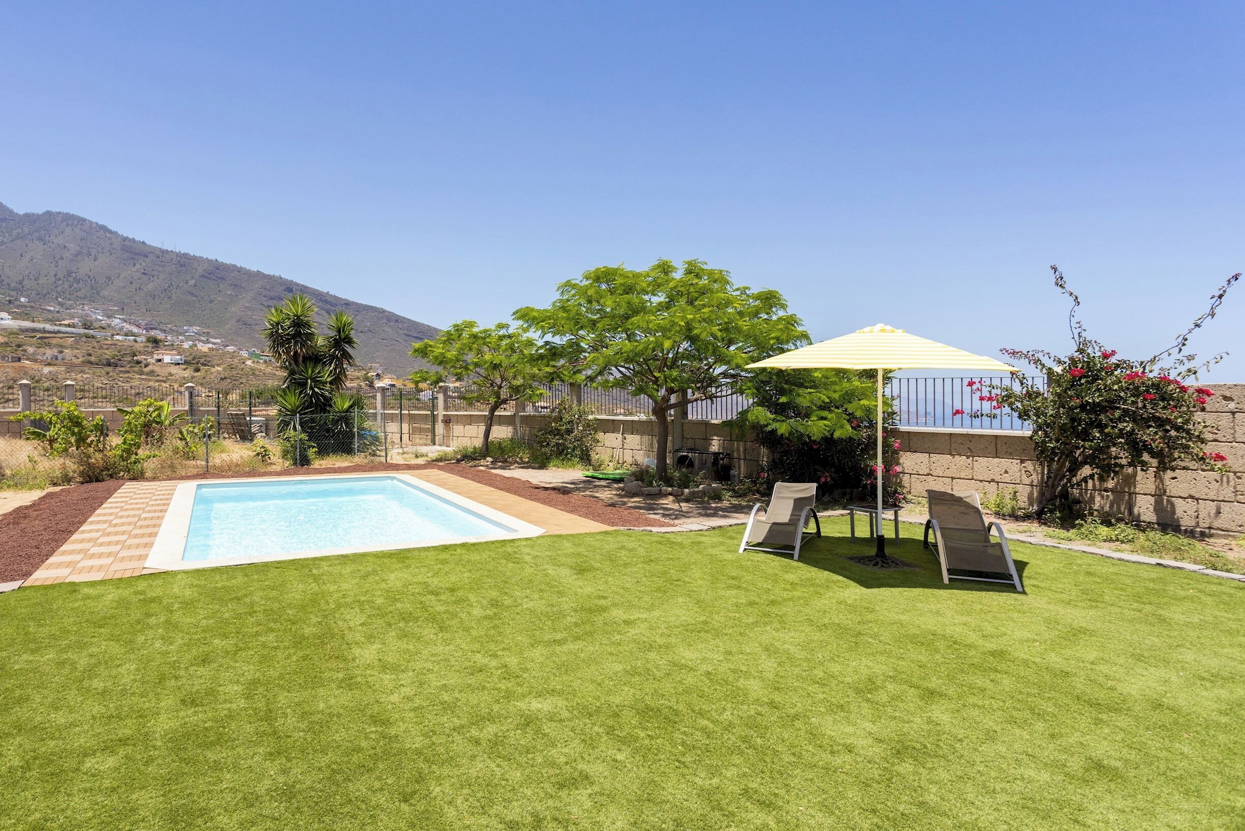 Un jardin avec une piscine, un patio couvert et une vue sur une montagne.