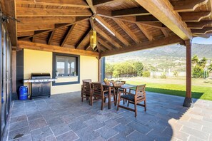An outdoor patio with a wooden ceiling, a barbecue grill, and a table with chairs. - Home2Book Villa Jazmín Real Heated pool & views (Arafo)