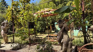 Un jardín con estatuas, una pérgola y un espacio de estar al aire libre de estilo rústico.