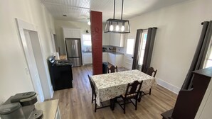 Una cocina amplia con electrodomésticos modernos, una zona de comedor con mesa y sillas, y un salón visible con chimenea.