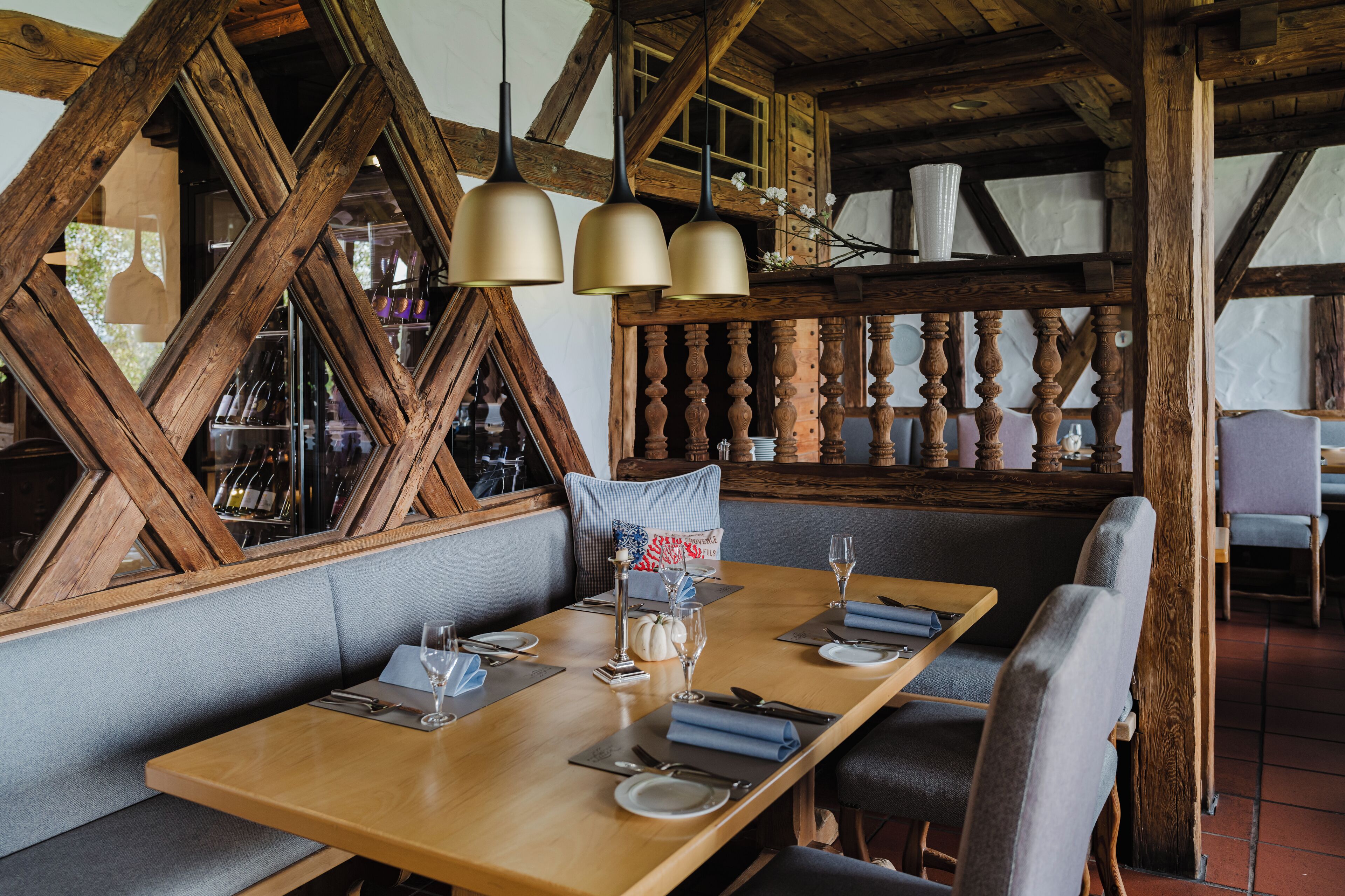 A restaurant with a wooden interior, a long table set for dining, and hanging pendant lights.
