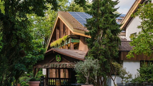 Un hôtel au design rustique, avec une façade en bois, un balcon et un panneau solaire sur le toit.