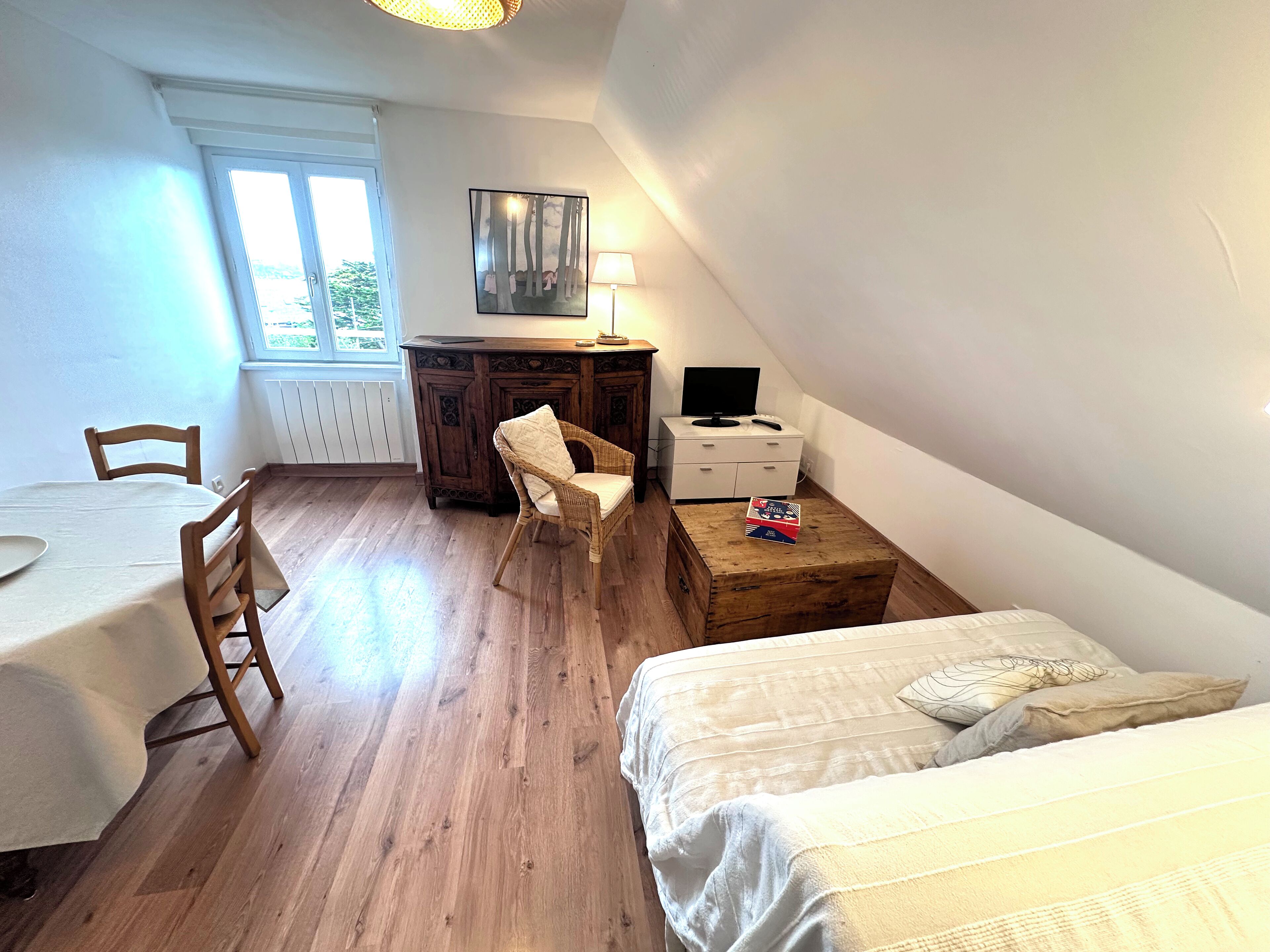 Une petite pièce, bien rangée, avec un lit, un bureau, une chaise et une table.