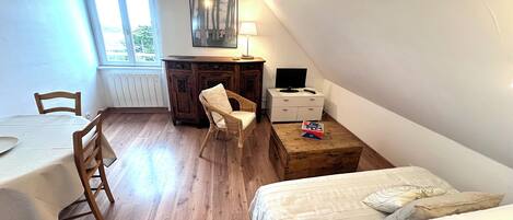 Une petite pièce, bien rangée, avec un lit, un bureau, une chaise et une table.