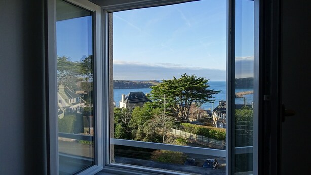 Ein Fenster mit Blick auf eine Küstenstadt, darunter Häuser und ein Gewässer.