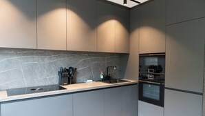 A modern kitchen with grey cabinets, a black countertop, and a built-in oven. - Exclusive designer apartment (Bad Honnef)
