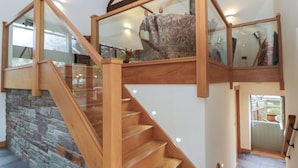A wooden staircase with glass railings leading to a second-floor landing. - The Barn at Sunny Barn (Brecon)