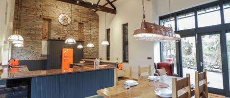 Una cocina amplia con pared de piedra, vigas de madera e iluminación colgante.