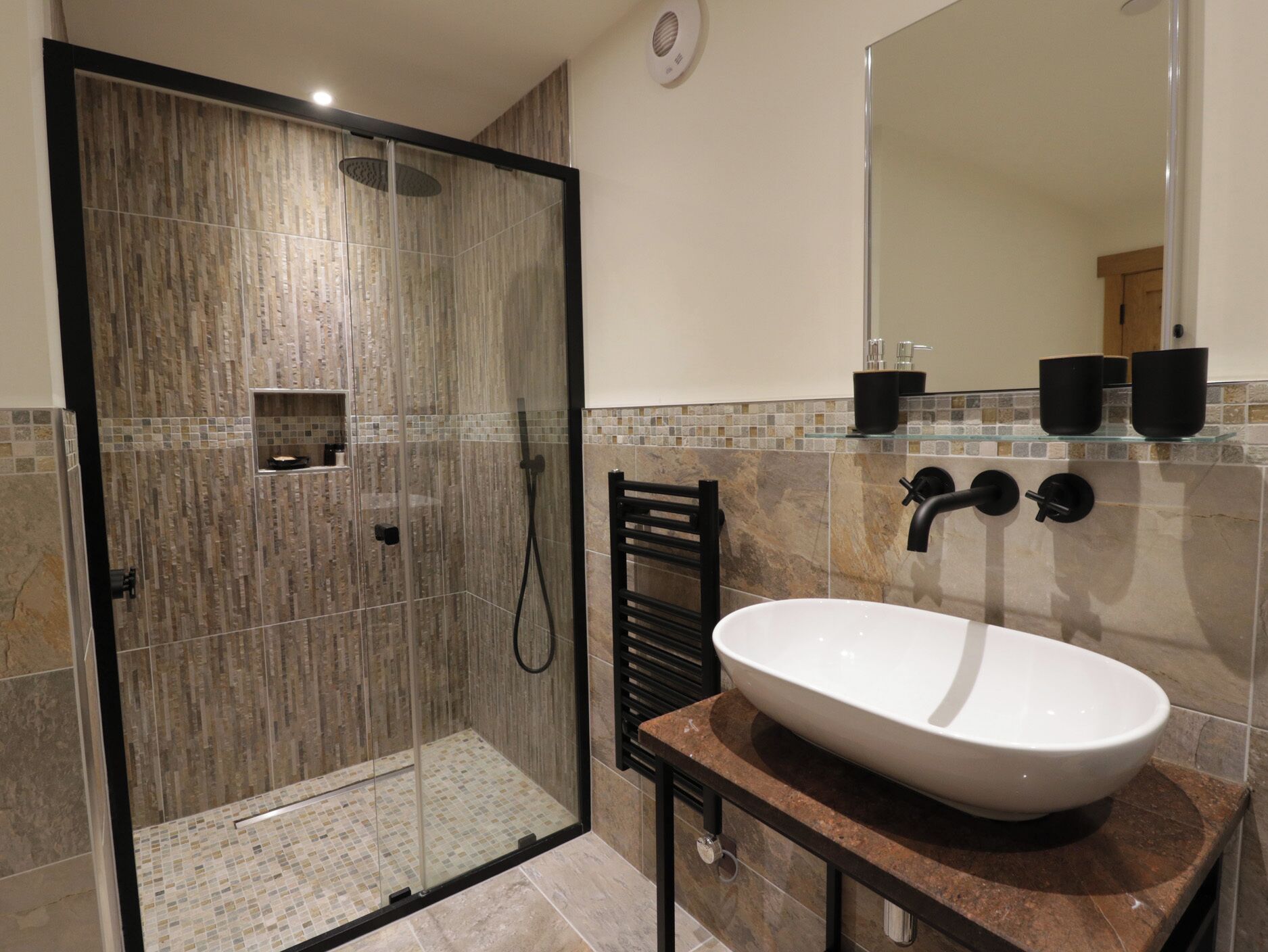 A modern bathroom with a glass-enclosed shower, a white sink, and a tiled backsplash.