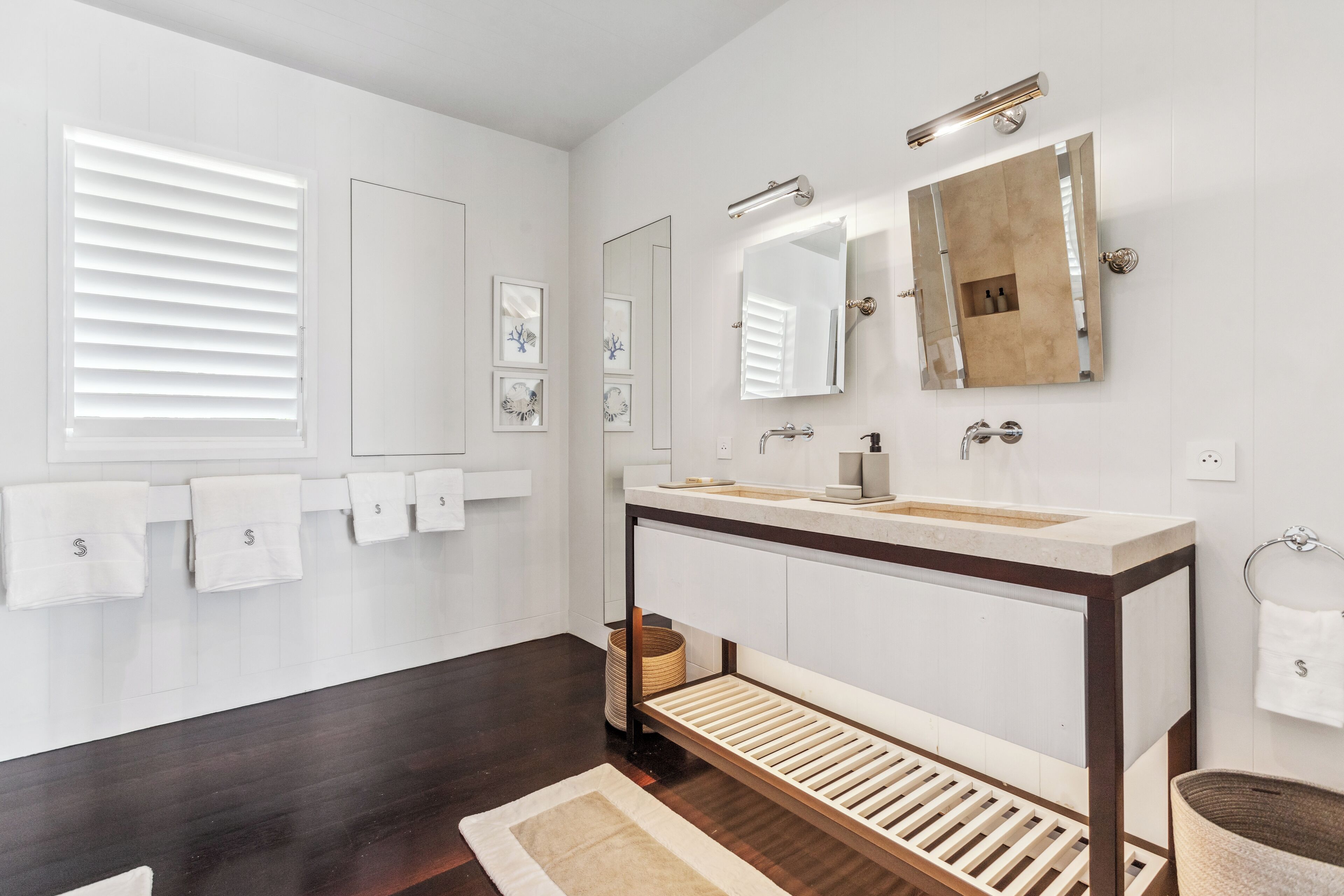 Une salle de bain moderne avec un grand miroir, un meuble-lavabo et un porte-serviettes muni de plusieurs serviettes.