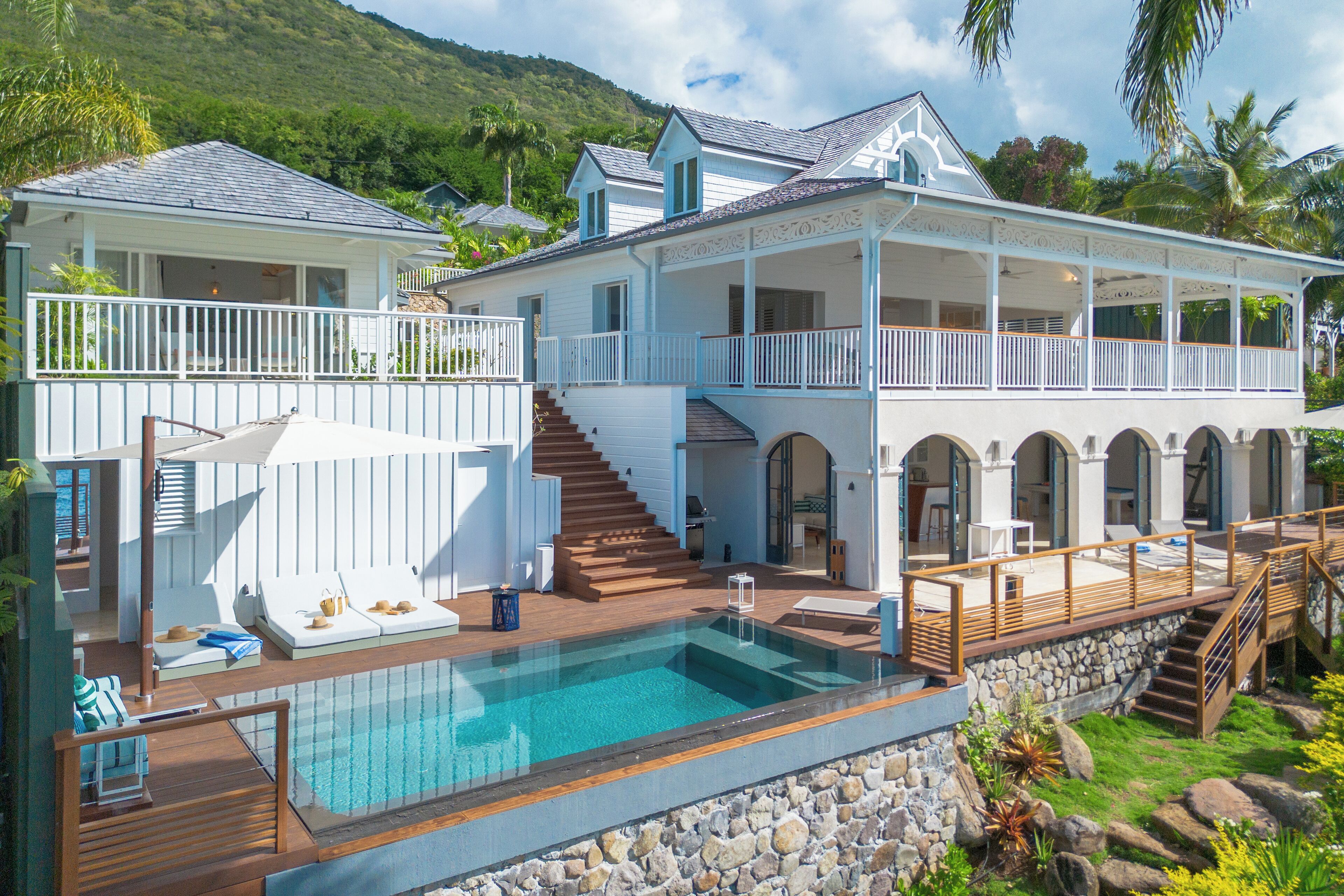 Une grande maison dotée d’une piscine, d’une terrasse couverte et d’un escalier menant à un deuxième étage.