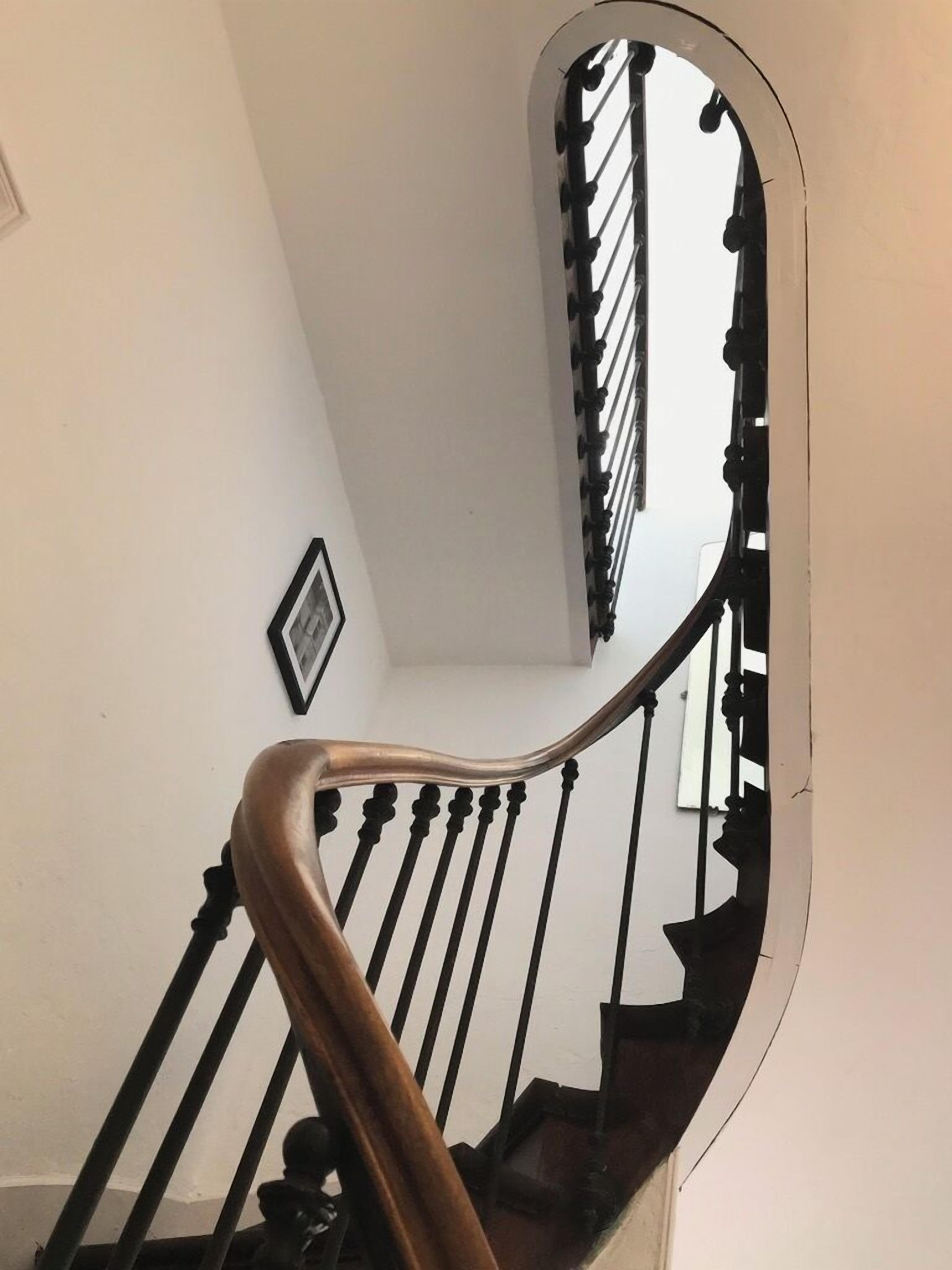 A staircase with a wooden handrail and black balusters.