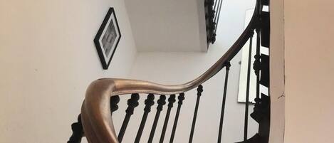 A staircase with a wooden handrail and black balusters.
