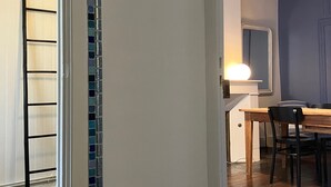 Um corredor com piso de azulejos, uma porta de madeira e uma área de jantar com mesa e cadeiras.