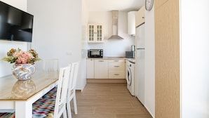 Una cocina moderna con una televisión de pantalla plana, un microondas, una lavadora y un armario con un reloj.