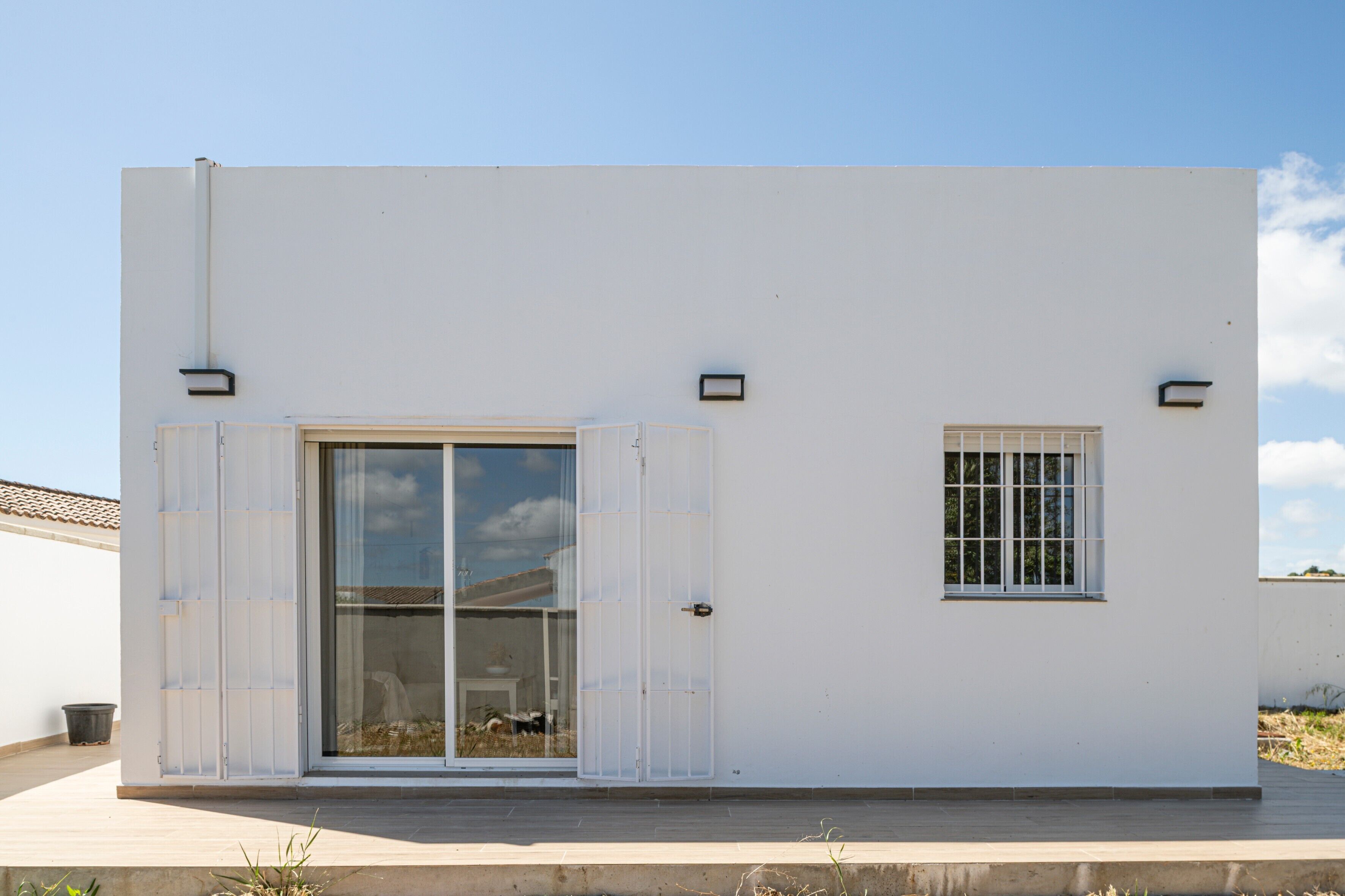 A modern building with a large sliding glass door, a small window, and a clean, white exterior.