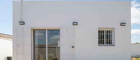 A modern building with a large sliding glass door, a small window, and a clean, white exterior.