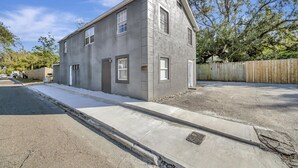 En tvåvånings bostadsbyggnad med en fasad av betong, ett garage framtill och ett staket av trä.