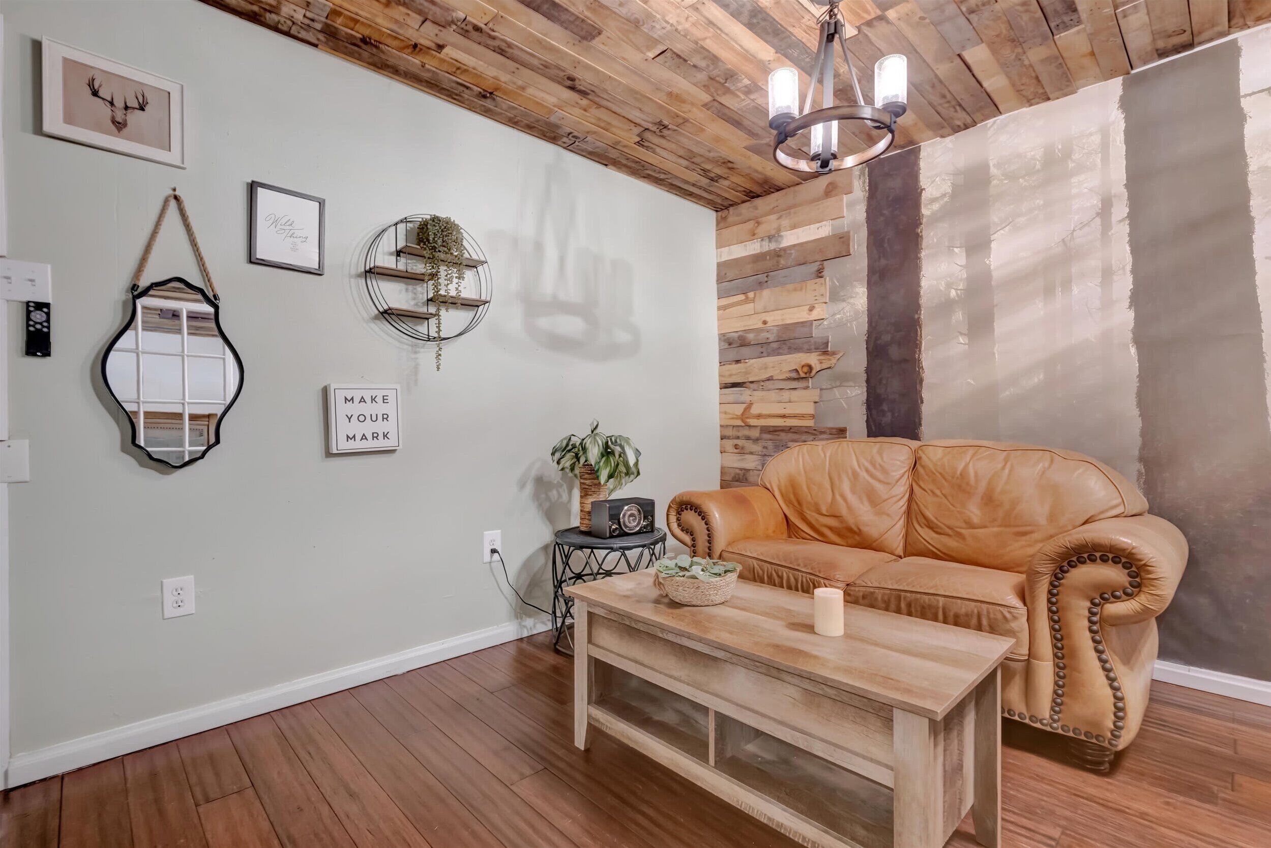 A cozy living room with a leather sofa, a wooden coffee table, and a chandelier.