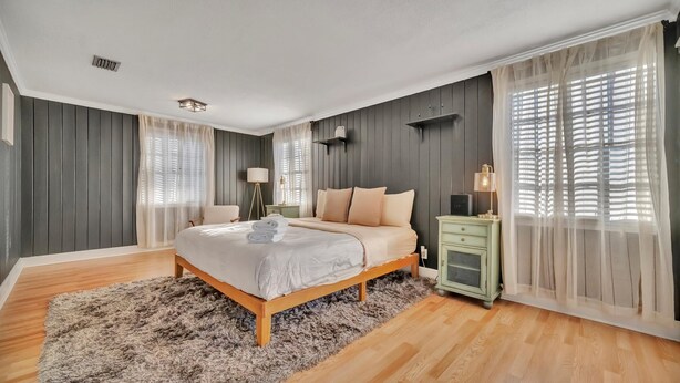 A bedroom with a large bed, wooden floor, grey walls, and a green nightstand. - Contemporary 2B, Walk to Hyde Park | Pets Welcome (Tampa)