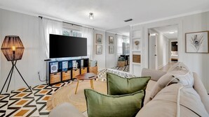 A modern living room with a large flat-screen TV, a sofa, a floor lamp, and a patterned rug. - Contemporary 2B, Walk to Hyde Park | Pets Welcome (Tampa)