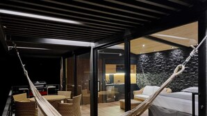 Un interior moderno con una hamaca, muebles de mimbre, una cama y una pared de piedra.