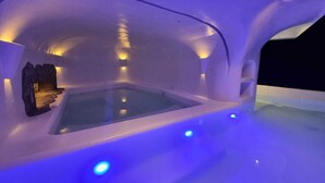 Habitación de hotel de hielo con piscina central, iluminada por luces azules.