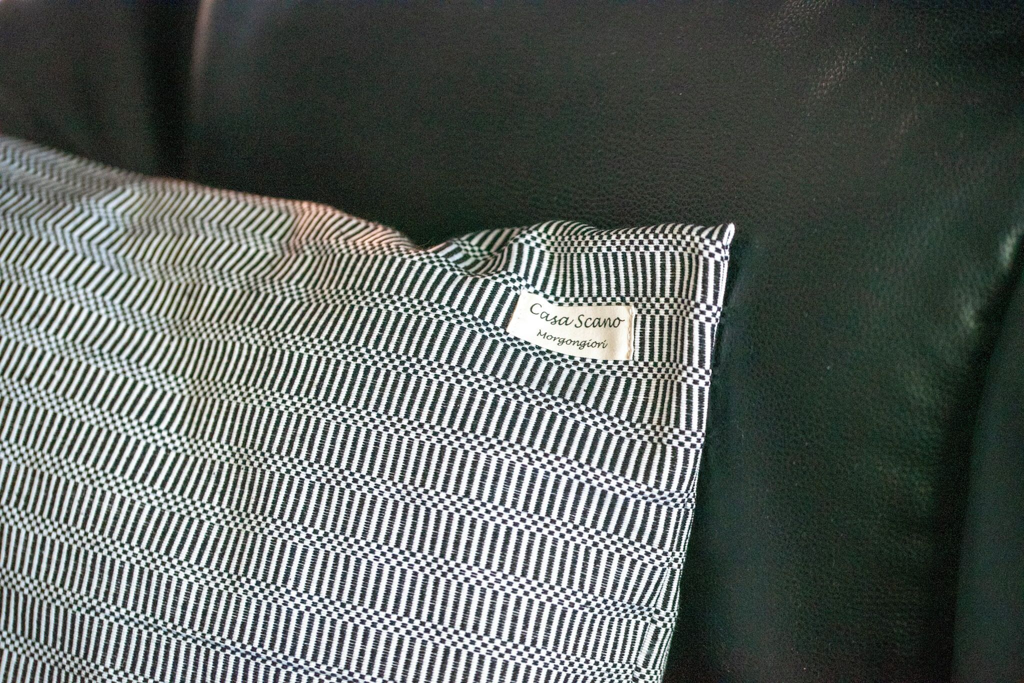 A black and white checkered pillow with a label reading "Casa Scano."
