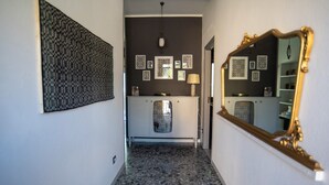 Ein Flur mit einem gemusterten Boden, einem weißen Schrank mit Dekorationsobjekten und einem großen Spiegel mit aufwendigem Rahmen.