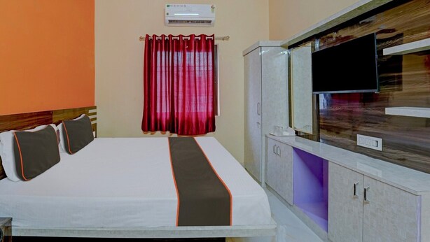 A hotel room with a bed, a television, a wardrobe, and an air conditioning unit. - Super Hotel O Siddhi Vinayak Hotel & Banquets (Motihari)