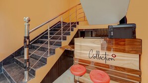 A staircase with a metal railing, a wooden bench with a sign reading "Collection", and a printer on a desk. - Super Hotel O Siddhi Vinayak Hotel & Banquets (Motihari)