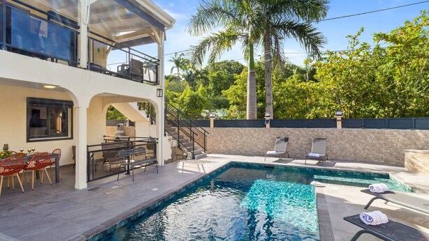 A two-story house with a pool, outdoor seating, and a staircase leading to the upper level.