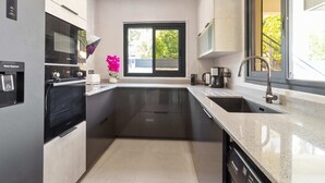 A modern kitchen with a water dispenser, a built-in oven, a coffee maker, and a dishwasher.