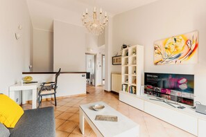 Een moderne woonkamer met een flatscreen-televisie, een eethoek en een kroonluchter.
