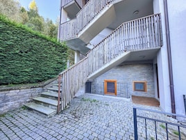 Un edificio de varios pisos con fachada de piedra, una escalera con barandillas de metal y una pequeña entrada con puerta de madera.