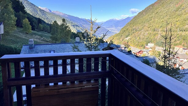 A wooden deck with a view of a valley and mountains.