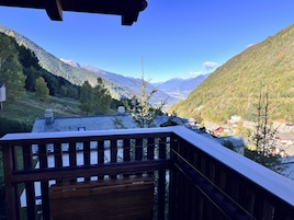 Una terraza de madera con vista a un valle y montañas.