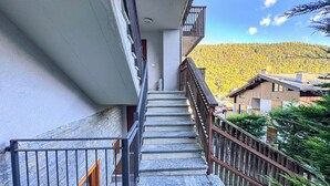 A staircase leading to a balcony with a view of a forested hillside.