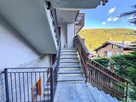 Una escalera conduce a un balcón con vistas a un paisaje boscoso.