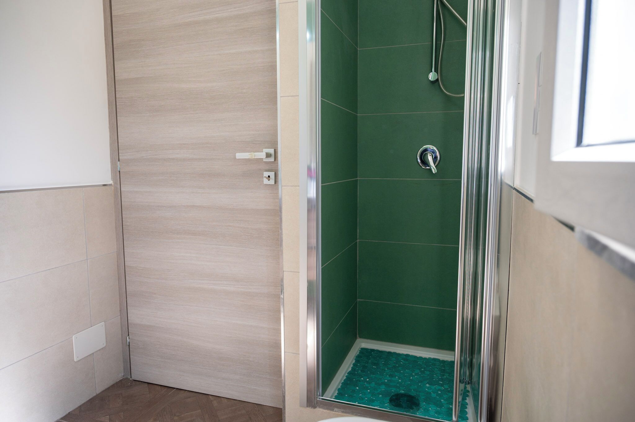 A bathroom with a shower, a door, and a tiled floor.