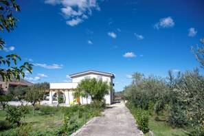 A white building with a flat roof, a covered outdoor area with a slide, and a paved pathway leading to it. - Villa Verde- Nature Holiday Home (Carini)